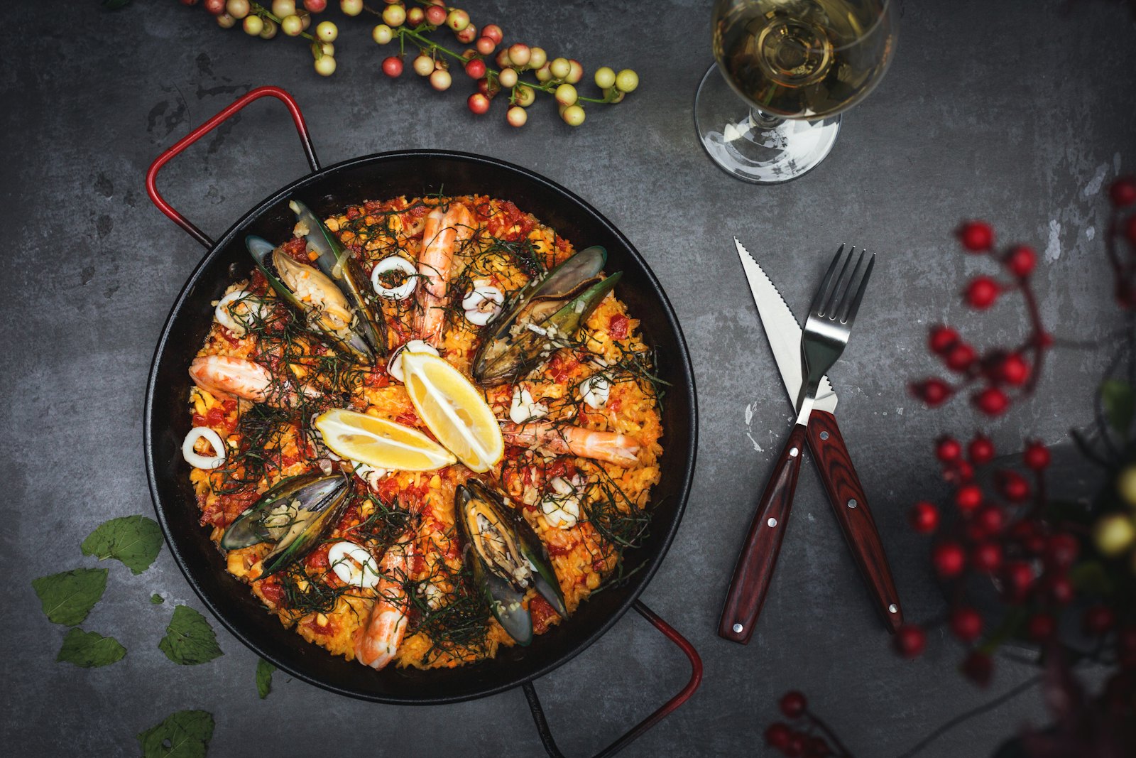 Seafood paella in a wide pan with prawns, mussels and lemon