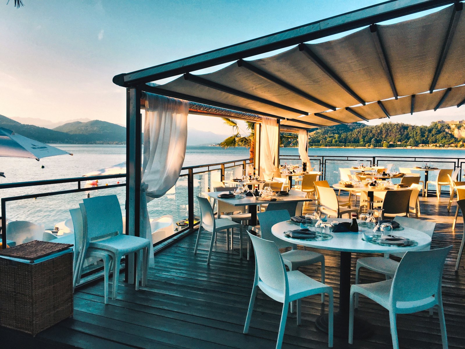 Sunlit Mediterranean restaurant terrace with set tables overlooking the sea